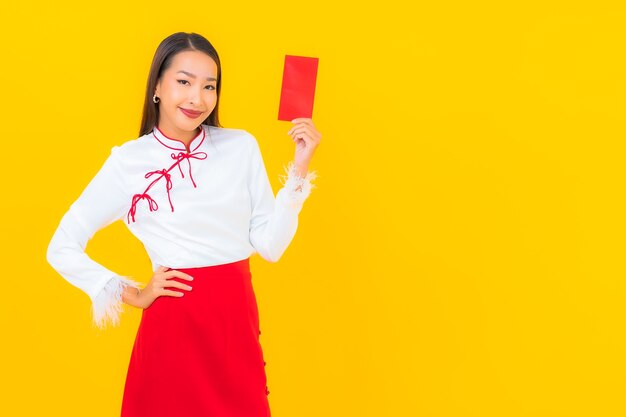 Portrait belle jeune femme asiatique avec des enveloppes rouges lettre au nouvel an chinois sur jaune