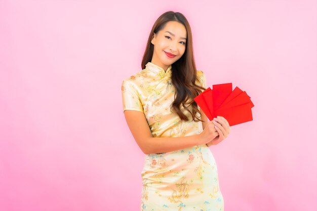 Portrait belle jeune femme asiatique avec des enveloppes rouges sur mur rose