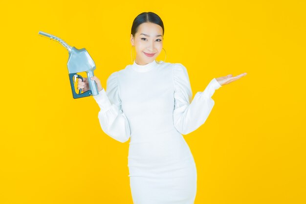 Portrait belle jeune femme asiatique feul pompe à essence sur jaune