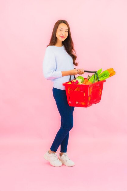 Portrait belle jeune femme asiatique avec fruits légumes et épicerie dans le panier sur le mur isolé rose