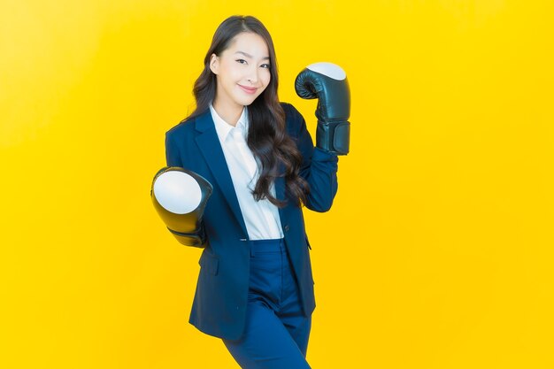 Portrait belle jeune femme asiatique avec gant de boxe sur jaune