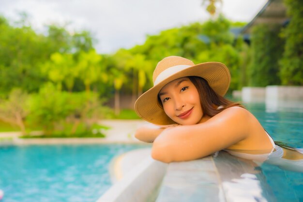 Portrait belle jeune femme asiatique heureux sourire se détendre autour de la piscine extérieure de l'hôtel