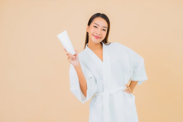 Portrait belle jeune femme asiatique avec lotion bouteille et crème pour le visage sur beige