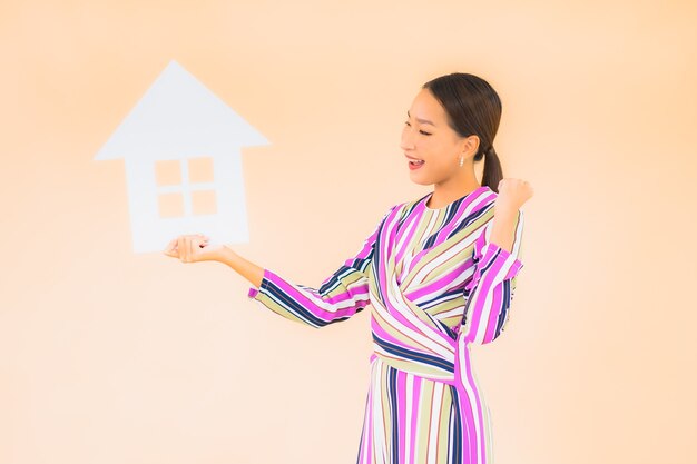 Portrait belle jeune femme asiatique avec maison ou maison signe papier sur couleur