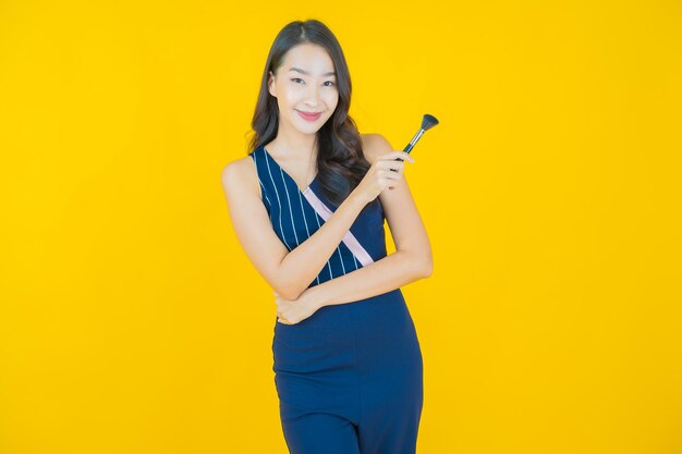 Portrait belle jeune femme asiatique avec maquillage pinceau cosmétique sur