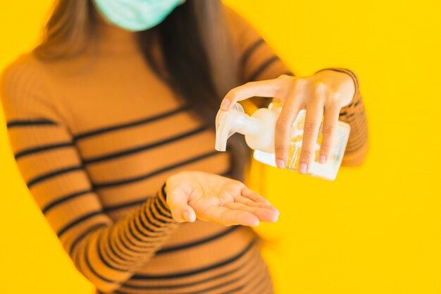 Portrait belle jeune femme asiatique avec masque vaporisateur d'alcool et bouteille de gel à la main pour se protéger du coronavirus ou covid19