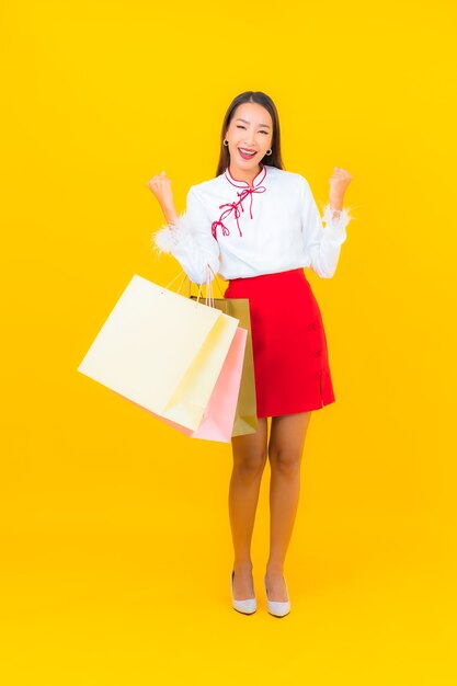 Portrait belle jeune femme asiatique avec panier et carte de crédit sur jaune