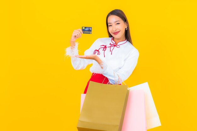 Portrait belle jeune femme asiatique avec panier et carte de crédit sur jaune