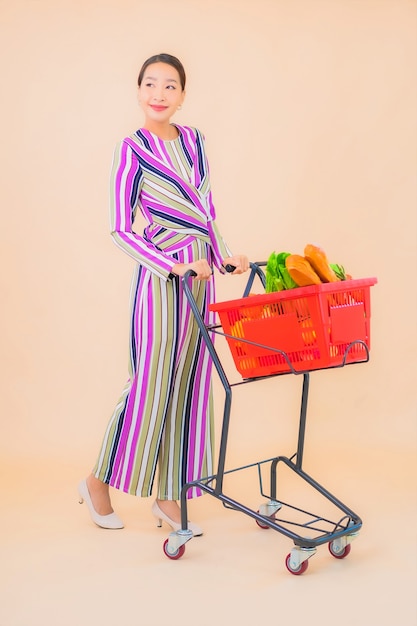 Portrait belle jeune femme asiatique avec panier d'épicerie de supermarché sur la couleur