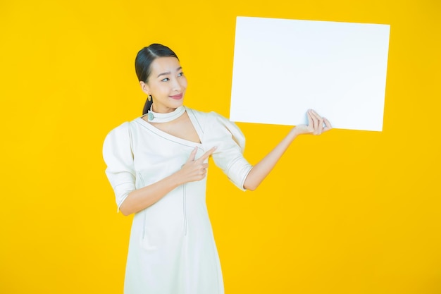 Portrait belle jeune femme asiatique avec panneau d'affichage blanc vide sur fond de couleur