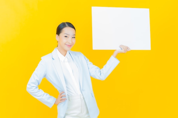 Portrait belle jeune femme asiatique avec panneau blanc vide sur jaune