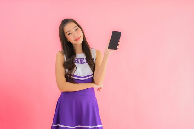 Portrait belle jeune femme asiatique pom-pom girl utiliser un téléphone mobile intelligent