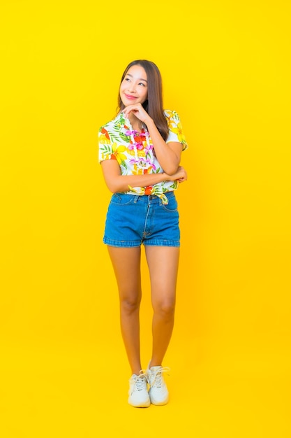 Portrait de la belle jeune femme asiatique portant une chemise colorée sur un mur jaune