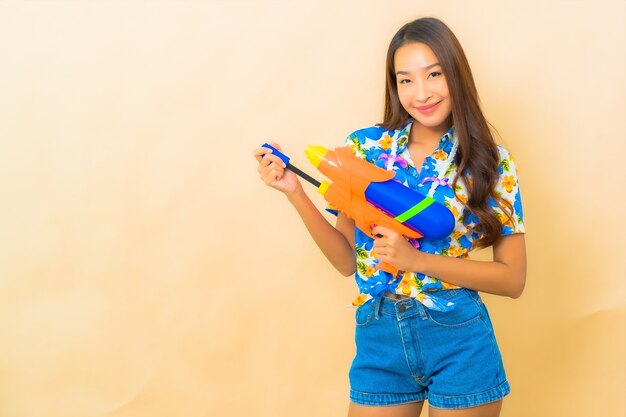 Portrait de la belle jeune femme asiatique portant une chemise colorée et tenant un pistolet à eau