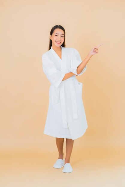 Portrait belle jeune femme asiatique portant peignoir avec sourire sur beige