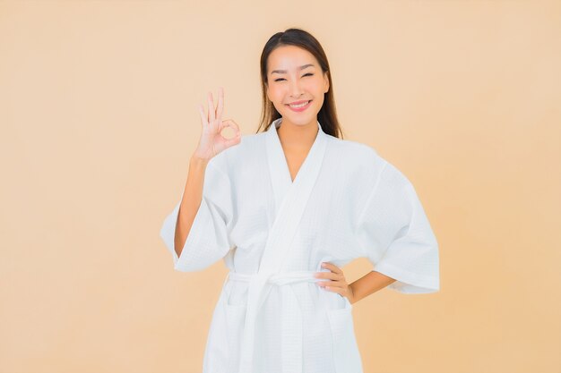 Portrait belle jeune femme asiatique portant peignoir avec sourire sur beige