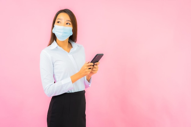 Portrait belle jeune femme asiatique porte un masque pour se protéger du covid19 et du coronavirus sur le mur rose