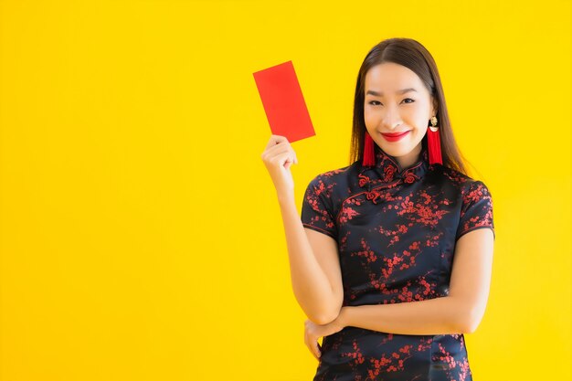 Portrait de la belle jeune femme asiatique porte une robe chinoise et détient une lettre rouge