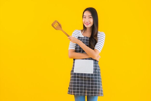 Portrait belle jeune femme asiatique porter un tablier avec pan noir et spatule