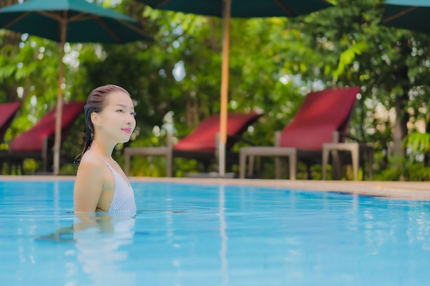 Portrait belle jeune femme asiatique profiter de se détendre sourire loisirs autour de la piscine extérieure dans l'hôtel