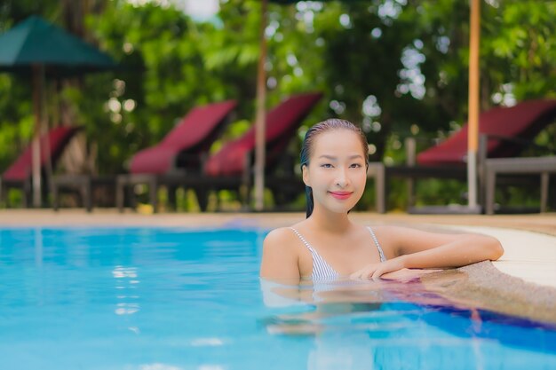 Portrait belle jeune femme asiatique profiter de se détendre sourire loisirs autour de la piscine extérieure dans l'hôtel