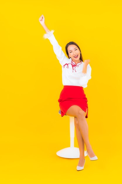 Portrait belle jeune femme asiatique s'asseoir sur une chaise sur jaune