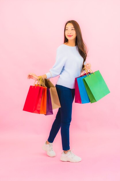 Portrait belle jeune femme asiatique avec sac à provisions coloré sur mur isolé de couleur rose