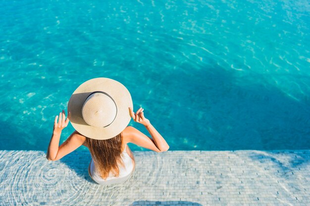 Portrait belle jeune femme asiatique se détendre autour de la piscine extérieure avec vue sur la ville