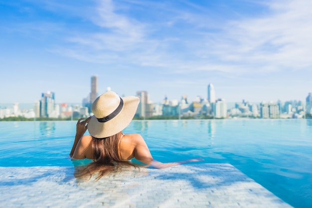 Portrait belle jeune femme asiatique se détendre autour de la piscine extérieure avec vue sur la ville