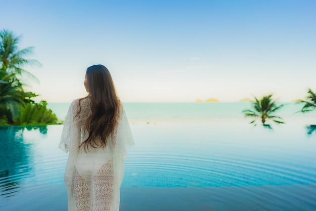 Portrait belle jeune femme asiatique se détendre dans la piscine extérieure de luxe dans l'hôtel resort près de la mer