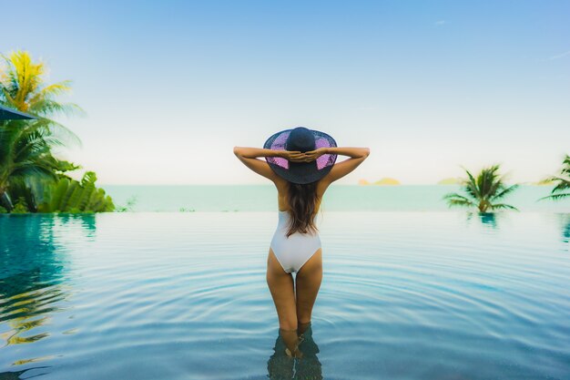 Portrait belle jeune femme asiatique se détendre dans la piscine extérieure de luxe dans l'hôtel resort près de la mer