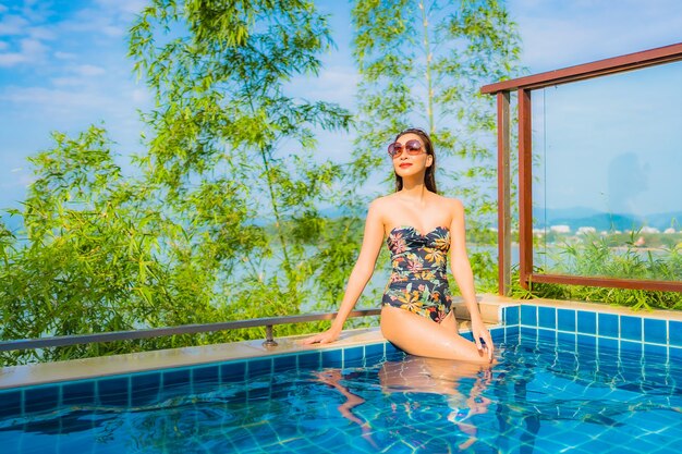 Portrait de la belle jeune femme asiatique se détendre dans la piscine extérieure avec vue mer océan