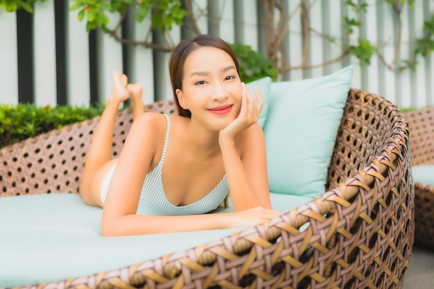 Portrait belle jeune femme asiatique se détendre les loisirs autour de la piscine extérieure dans la station de l'hôtel pour les vacances de voyage