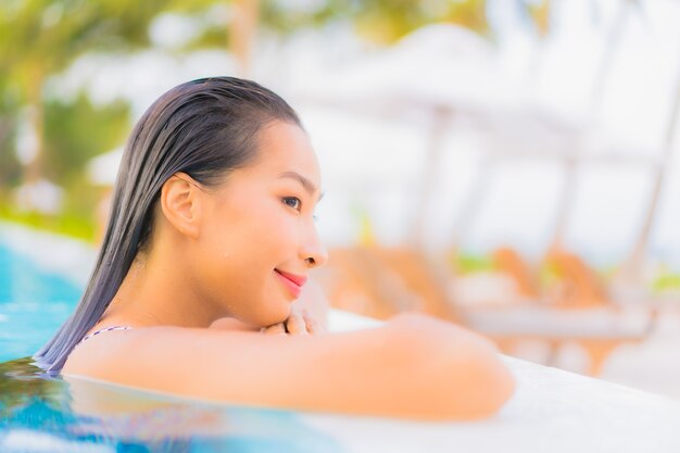 Portrait belle jeune femme asiatique se détendre les loisirs autour de la piscine extérieure avec mer océan plage