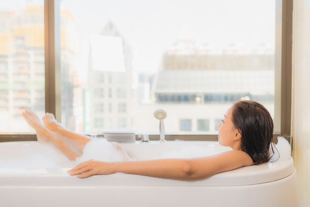 Portrait belle jeune femme asiatique se détendre profiter de prendre un bain à la baignoire à l'intérieur de la salle de bain