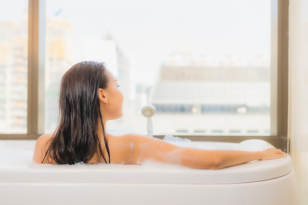 Photo gratuite portrait belle jeune femme asiatique se détendre profiter de prendre un bain à la baignoire à l'intérieur de la salle de bain