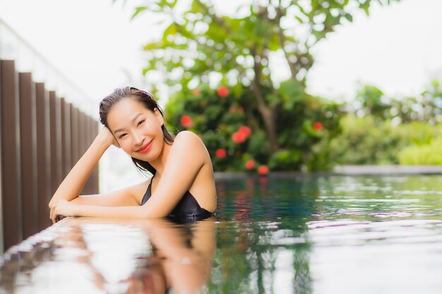 Portrait belle jeune femme asiatique se détendre sourire autour de la piscine extérieure dans l'hôtel resort