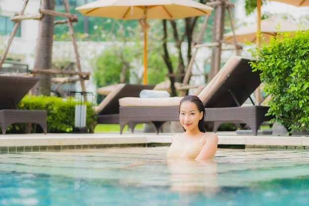 Portrait belle jeune femme asiatique se détendre sourire autour de la piscine extérieure dans l'hôtel resort