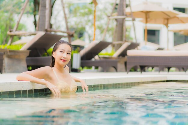 Portrait belle jeune femme asiatique se détendre sourire autour de la piscine extérieure dans l'hôtel resort