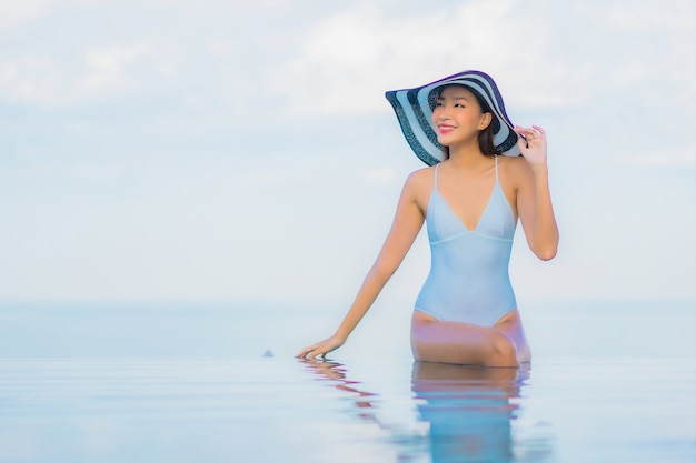 Portrait belle jeune femme asiatique se détendre sourire autour de la piscine extérieure dans l'hôtel resort