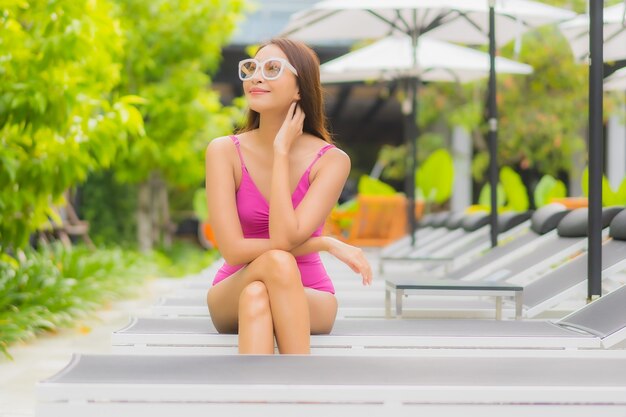 Portrait belle jeune femme asiatique se détendre sourire autour de la piscine extérieure dans l'hôtel resort