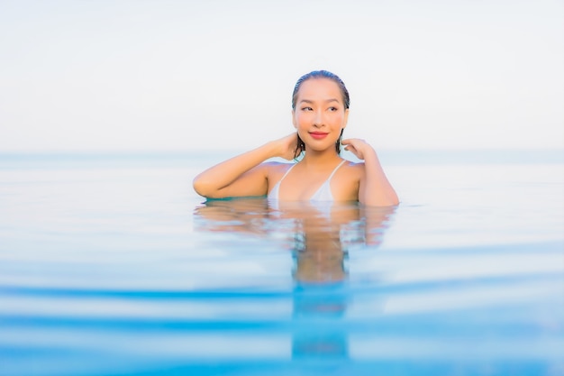 Portrait belle jeune femme asiatique se détendre sourire autour de la piscine extérieure dans l'hôtel resort