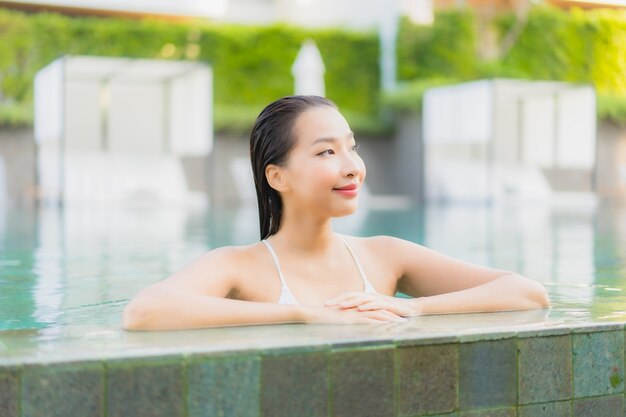 Portrait belle jeune femme asiatique se détendre sourire autour de la piscine extérieure dans l'hôtel resort