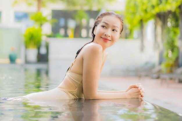 Portrait belle jeune femme asiatique se détendre sourire autour de la piscine extérieure dans la station de l'hôtel en voyage de vacances