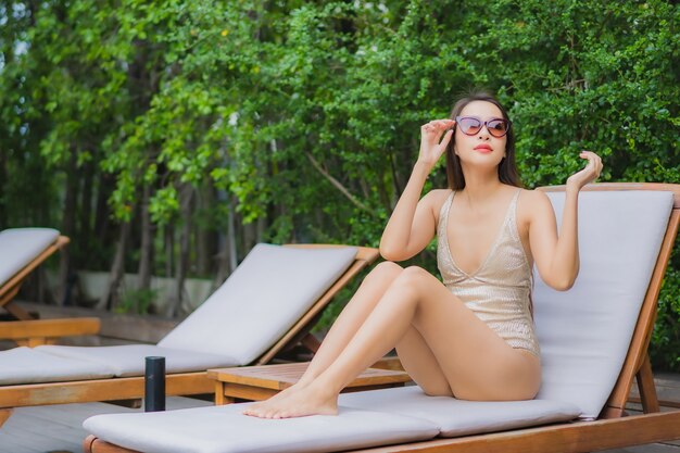 Portrait belle jeune femme asiatique se détendre sourire autour de la piscine extérieure