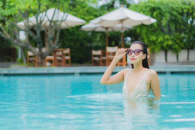 Portrait belle jeune femme asiatique se détendre sourire autour de la piscine extérieure