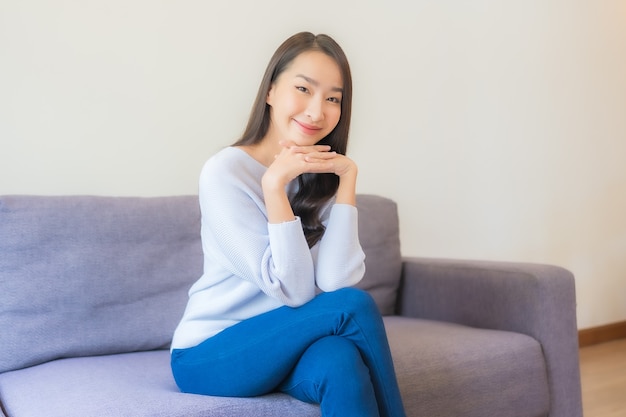 Portrait belle jeune femme asiatique se détendre sourire sur canapé dans le salon