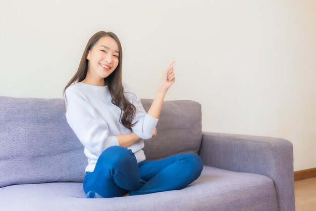 Portrait belle jeune femme asiatique se détendre sourire sur canapé dans le salon