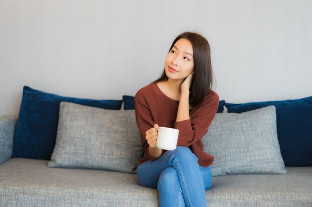 Portrait belle jeune femme asiatique se détendre sourire sur le canapé à l'intérieur du salon