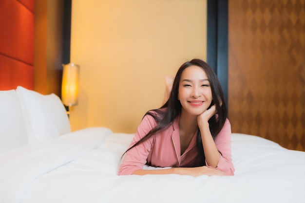 Portrait belle jeune femme asiatique se détendre sourire heureux sur le lit à l'intérieur de la chambre